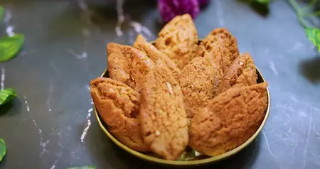 Fried shakarparas cooling on absorbent paper, ready to be stored in a container.