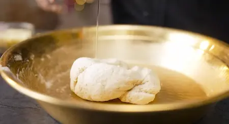 Mixing pizza dough ingredients and kneading to a smooth texture.