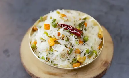 Garnishing Seviyan Upma with nuts and coriander