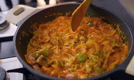 Finalizing Malai Pyaaz ki Sabzi with cream and spices