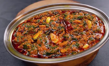 Lasuni Methi served in a bowl with roti on the side.