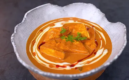 Garnished paneer korma served with naan and rice