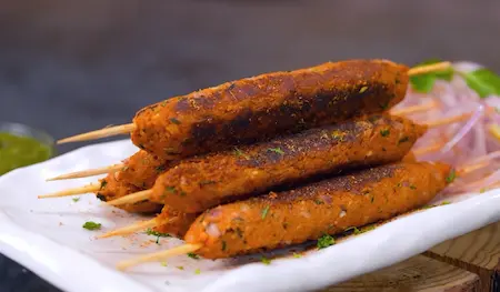 serving hot soyabean seekh with mint chutney, onion rings, and lemon wedges