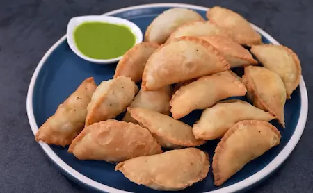 Cooling and serving crispy Holi Special Matar Gujiya on a plate