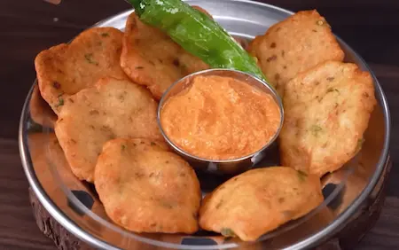 Serving hot crispy Udid Daliche Vade with peanut coconut chutney