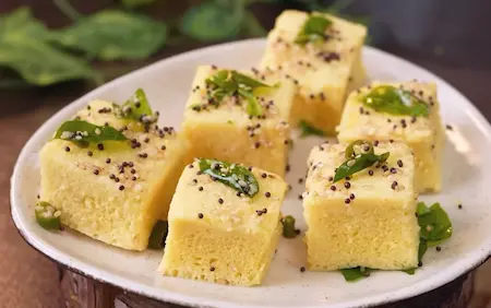 Step 10: pouring tempering over Soft & Spongy Market Style Khaman Dhokla Recipe
