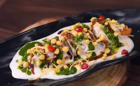 Step 7: Fully assembled Sindhi Dahi Mirchi Chaat topped with saunth chutney, dahi, sev and pomegranate seeds