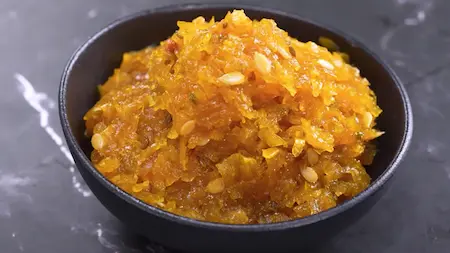 Serving Kaddu Ka Halwa garnished with melon seeds and chironji.