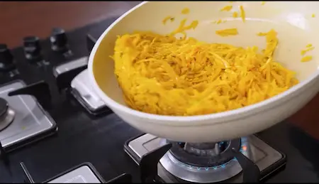 Stirring grated pumpkin in ghee for Kaddu Ka Halwa.