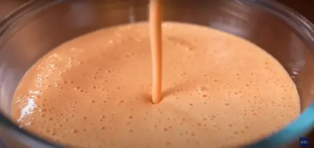 Adjusting the consistency of the tomato dosa batter by adding more water.