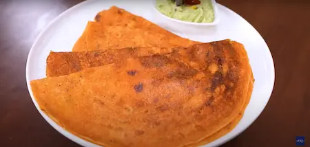  Serving crispy tomato dosa with a side of peanut and coconut chutney.