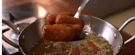 Koftas being fried in hot oil until golden brown.