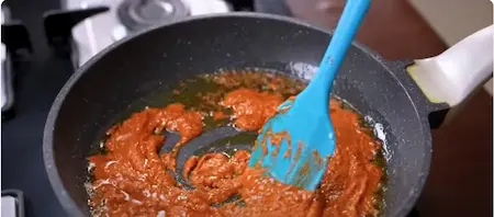 Cooking the red chili chutney in a pan.