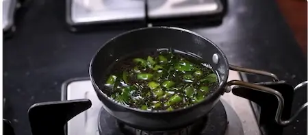 Pouring tempering over cut dhokla pieces.