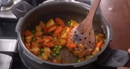 Adding green chillies and ginger-garlic paste to the Veg Pulao mixture.