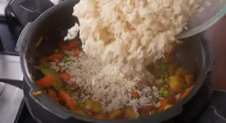 Adding tomatoes, garam masala, and coriander to the Veg Pulao.