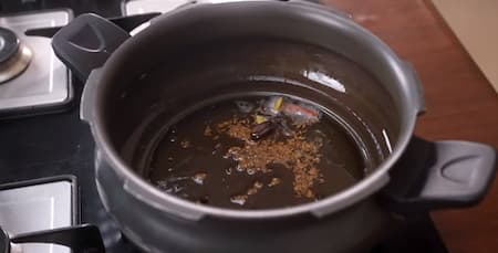 Adding whole spices to the pressure cooker for Veg Pulao.