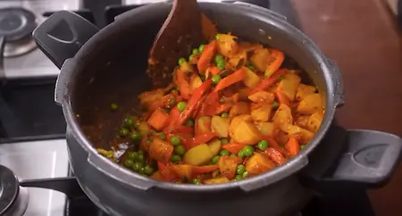 Cooking diced vegetables with spices in the Veg Pulao.