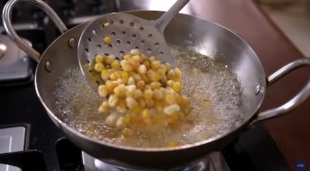 Corn kernels being fried in hot oil until golden and crispy.