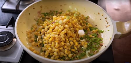 Adding the fried crispy corn to the sautéed vegetables and toss everything together.