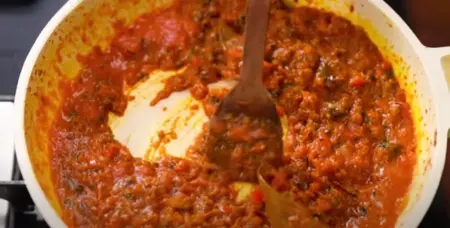 Rich and creamy masala gravy being poured over paneer and vegetables on a tawa.