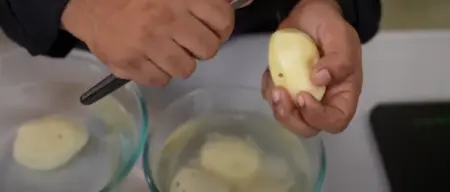 Grated potatoes being rinsed in water to remove excess starch.