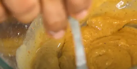 A bowl containing a thick batter made from white flour, corn flour, and seasonings, ready to coat paneer cubes for Paneer Manchurian.