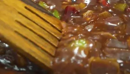 Cornflour slurry being poured into the pan to thicken the gravy for Paneer Manchurian.