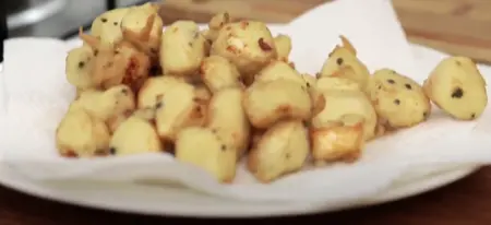 Paneer cubes being deep-fried in hot oil until golden brown.