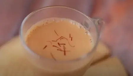 Kadak Chai with saffron strands, served in a cup.