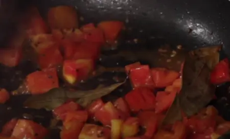 Tomato mixture cooking in the pan until softened for Sev Tamatar Nu Shak.