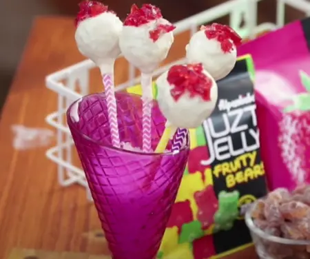 Garnishing cake pops with colorful sprinkles.