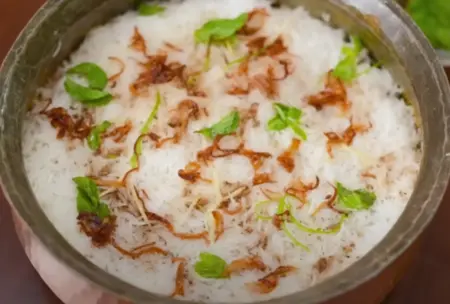 Layering mutton and rice for Mutton Biryani.