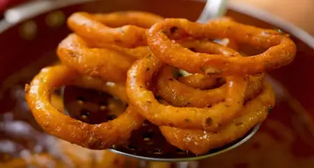 Potato rings frying in hot oil, turning golden brown and crispy.