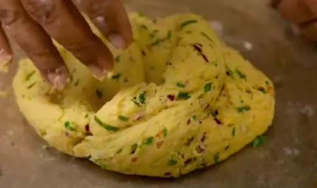 Sautéing garlic and chilli flakes in butter, with grated potatoes added, forming the base mixture for crispy potato rings.