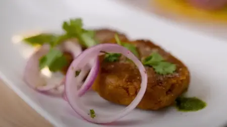 Garnished kebabs served with mint chutney, sliced onions, and chaat masala.