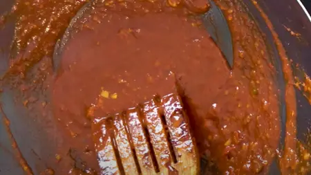 Peri Peri sauce being mixed in a wok with vinegar, soya sauce, and red chilli sauce.