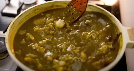 Cooking the sabzi with spices, besan, and boiled potatoes.