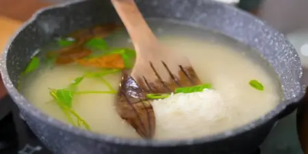 Biryani rice being prepared with aromatic spices and herbs.