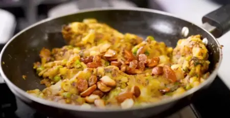 Sautéing spices with green peas, cashews, raisins, and mashed potatoes for stuffing.