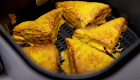 Bread pakoda pieces being air fried until golden brown and crispy.