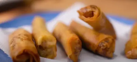 Spring rolls deep frying in hot oil until crispy and golden brown.