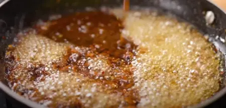 Thai sweet chili sauce being prepared with a mix of sugar, honey, vinegar, and chili flakes.