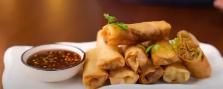 Crispy Veg Spring Rolls served on a plate with Thai sweet chili sauce.