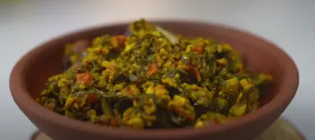 Radish leaves and moong dal being cooked together, with spices in the final stage of Mooli ke Patte ki Sabzi.