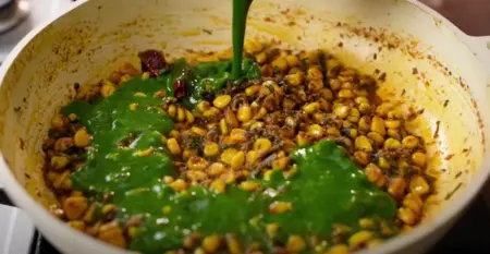 Cooking shredded spinach and corn kernels together for Palak Corn Ki Sabji.