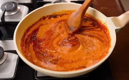 Mixing boiled peanuts with masala paste and spices for the final preparation of Peanuts Ki Sabji.