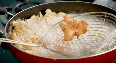 Chicken pieces frying in hot oil until golden brown for Chicken Popcorn.