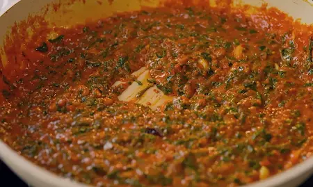 Cooked methi mixed with peanut-based gravy in a pan.