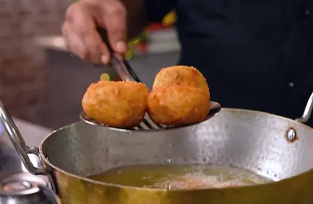 Golden brown fried mushrooms draining on a paper towel.